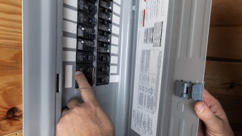 A person interacts with a circuit breaker panel.