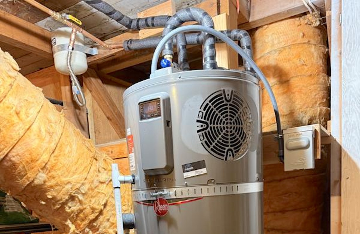 A Rheem water heater with connected pipes and insulation in a basement.