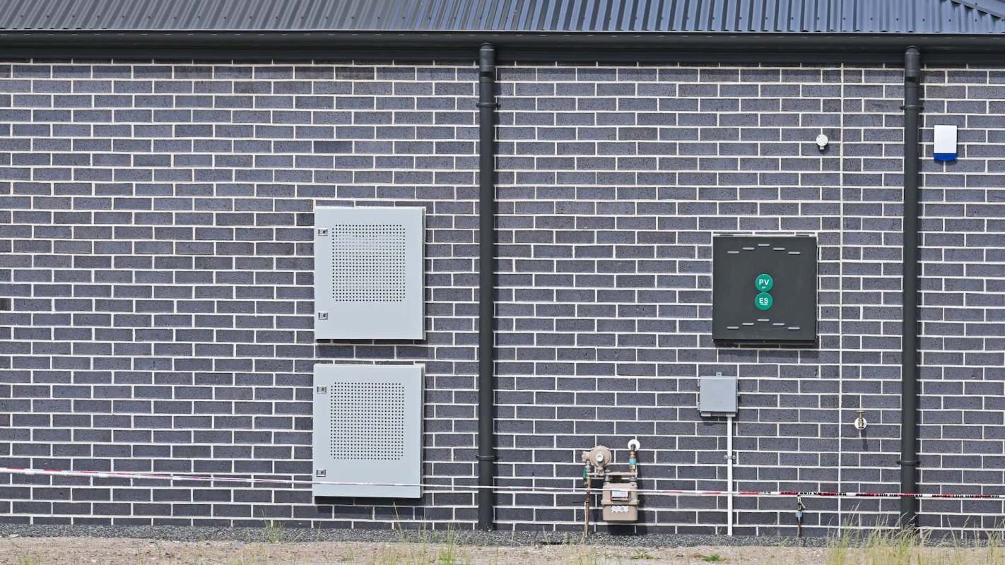 A gray brick wall with two utility boxes and a gas meter.