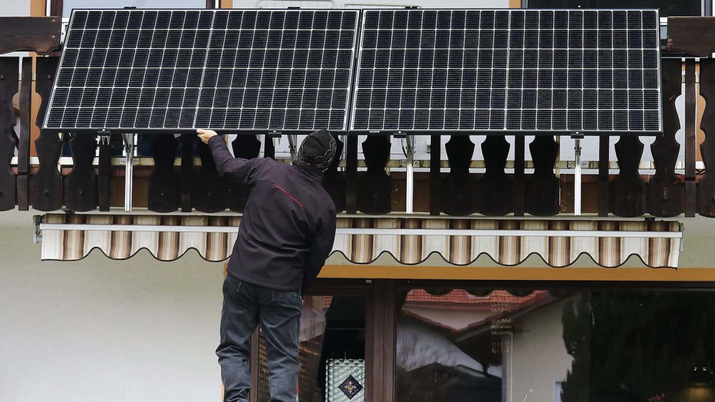 A person installs solar panels on a balcony.