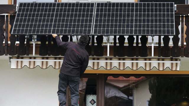 A person installs solar panels on a balcony.