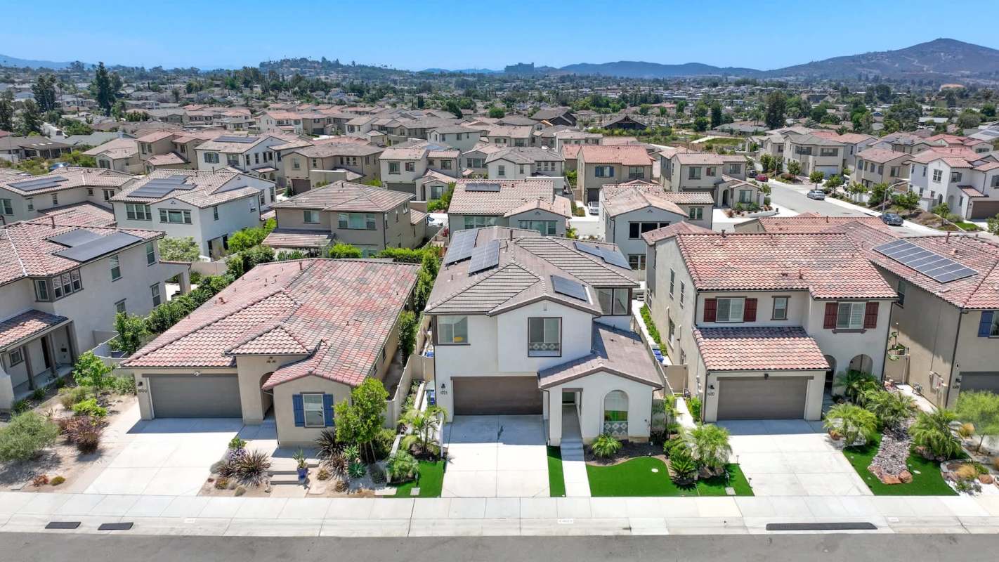 Aerial view of a suburban neighborhood with houses featuring red tile roofs and landscaped yards.