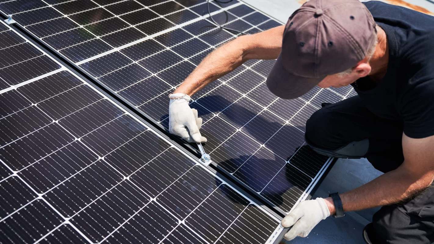 A person is installing a solar panel on a rooftop.