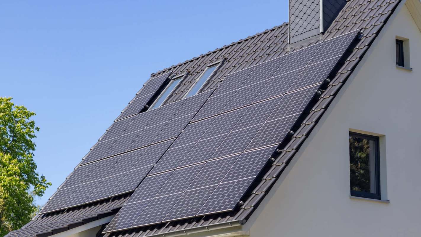 Solar panels installed on the roof of a house under a clear blue sky.