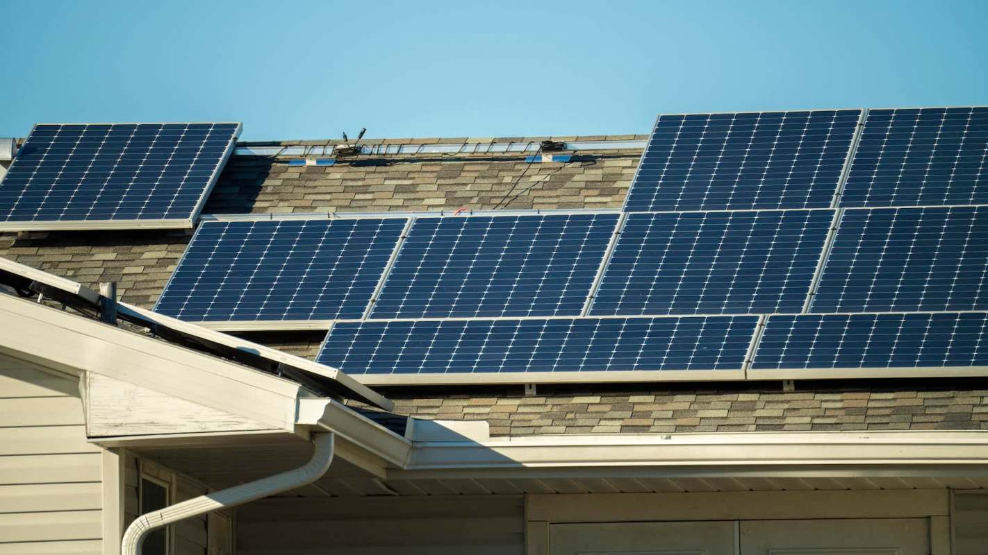 Solar panels installed on a sloped roof under a clear blue sky.