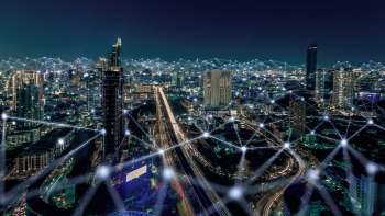 A city skyline at night with illuminated buildings and abstract network connections overlay.