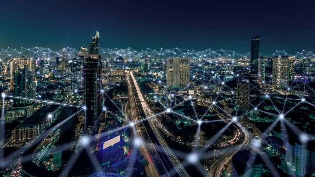 A city skyline at night with illuminated buildings and abstract network connections overlay.