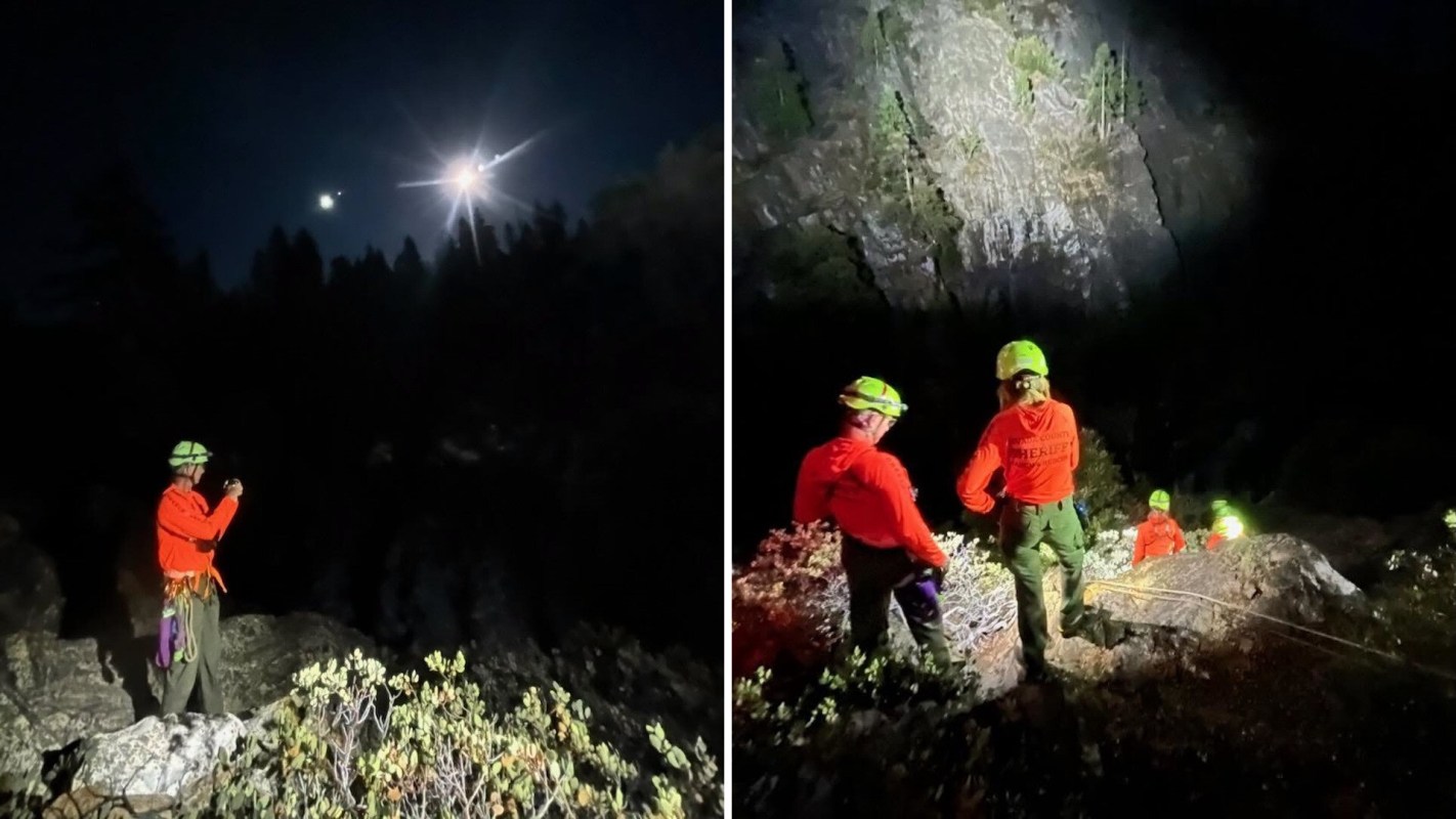 A group of climbers in safety gear work during the night near a rocky area, illuminated by headlamps.