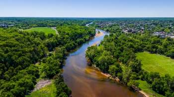 Aerial view of a winding Rappahannock River surrounded by lush green trees and open fields.