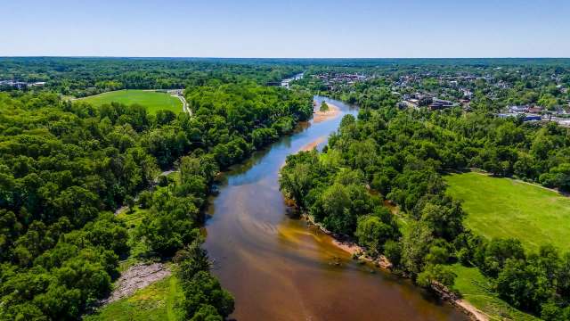 Aerial view of a winding Rappahannock River surrounded by lush green trees and open fields.