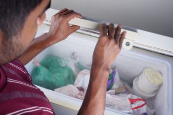 A man opening a chest freezer.