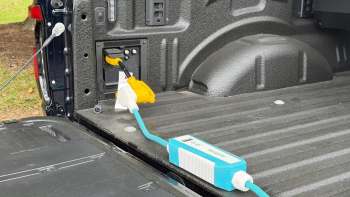 A power outlet and charger connected in the bed of a pickup truck.