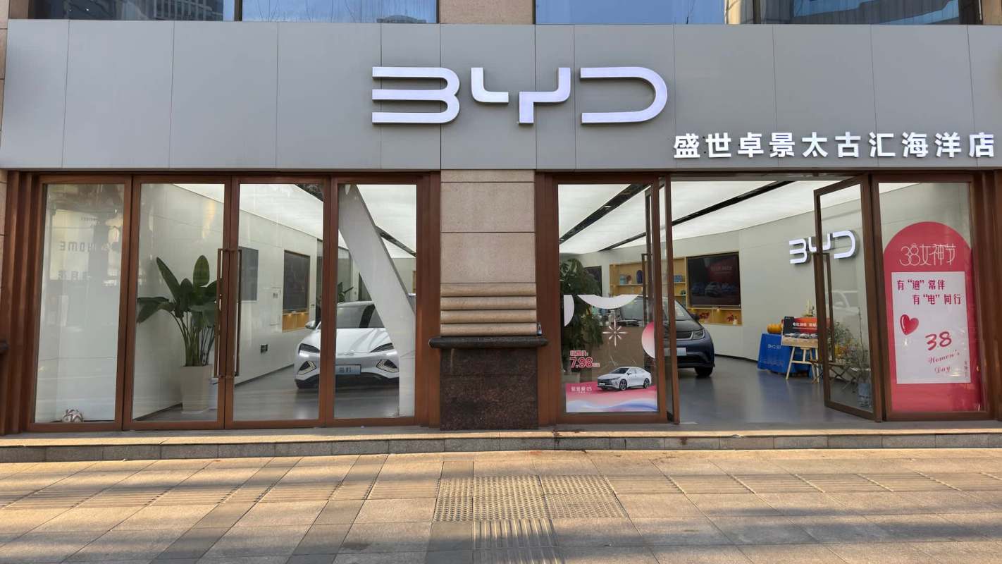 A BYD car dealership displaying electric vehicles and promotional signage in Chinese.