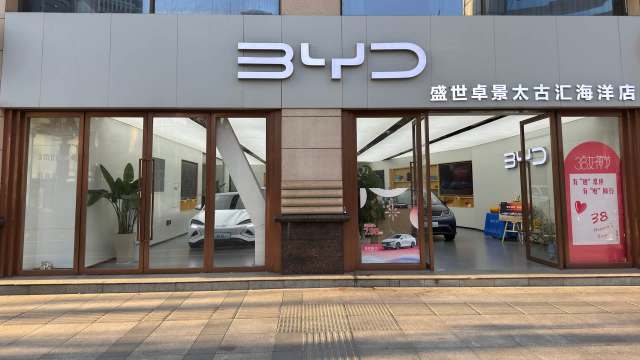 A BYD car dealership displaying electric vehicles and promotional signage in Chinese.