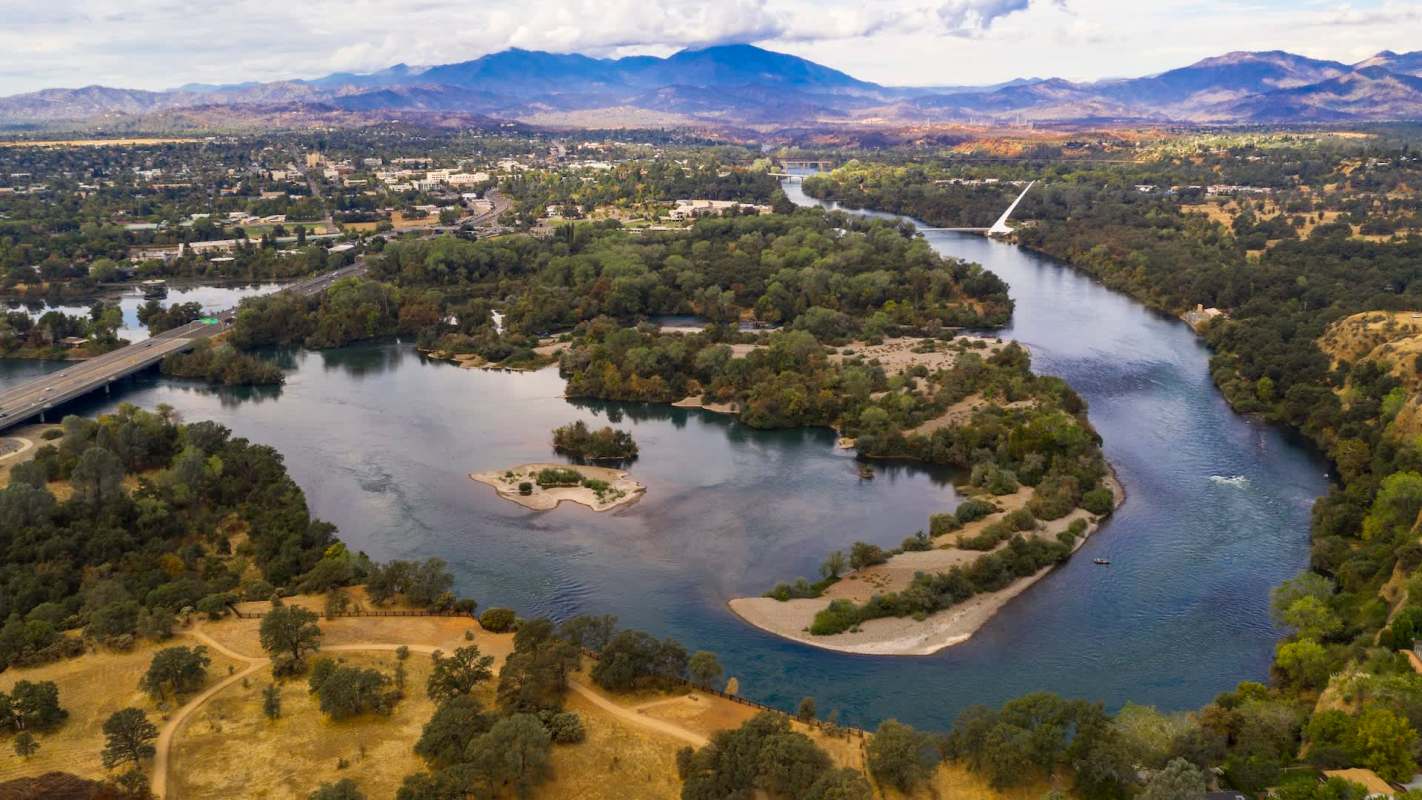 Aerial view of a river winding through a landscape of trees and hills.