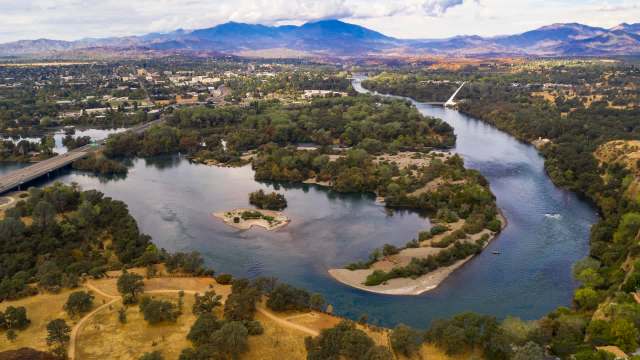 Aerial view of a river winding through a landscape of trees and hills.
