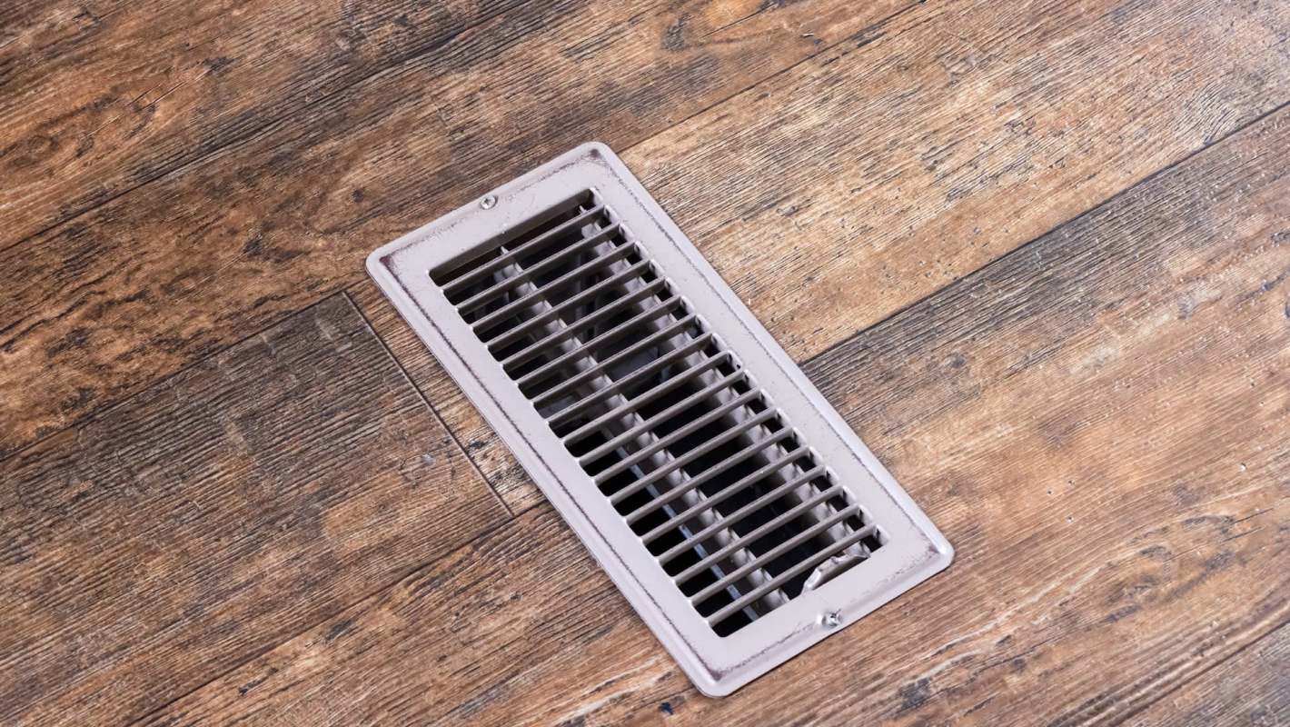 A floor vent on a wooden surface.