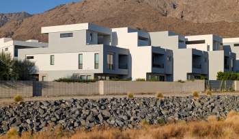 Modern residential buildings with a rocky landscape and mountainous background.