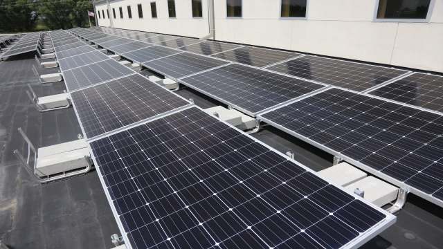 A flat roof covered with multiple solar panels.