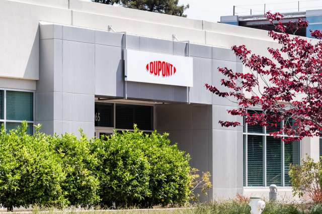 A building entrance featuring a sign that reads "DUPONT" and surrounding greenery.