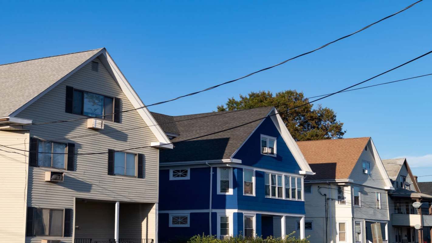 A row of houses with varying colors and architectural styles under a clear blue sky.
