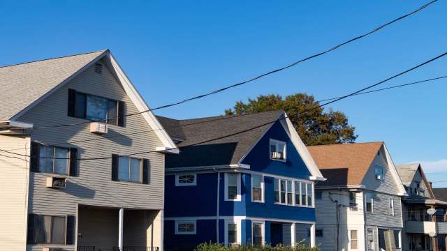A row of houses with varying colors and architectural styles under a clear blue sky.