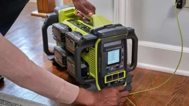 A person connects a battery power station to an electrical outlet on a wall.