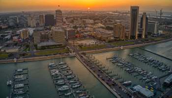A waterfront view of Corpus Christi, Texas, marina with boats and a skyline at sunset.