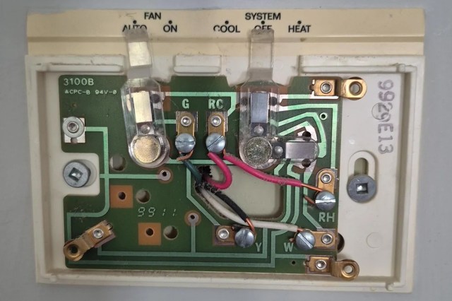 A circuit board from a thermostat showing various components and connections.