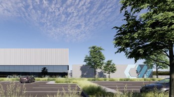 A data center with glass windows, surrounded by trees and a parking lot.
