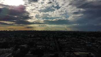 A panoramic view of a city skyline under a cloudy sky at sunset.