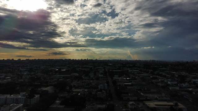 A panoramic view of a city skyline under a cloudy sky at sunset.