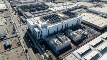An aerial view of an industrial site with multiple buildings and solar panels on the roof.