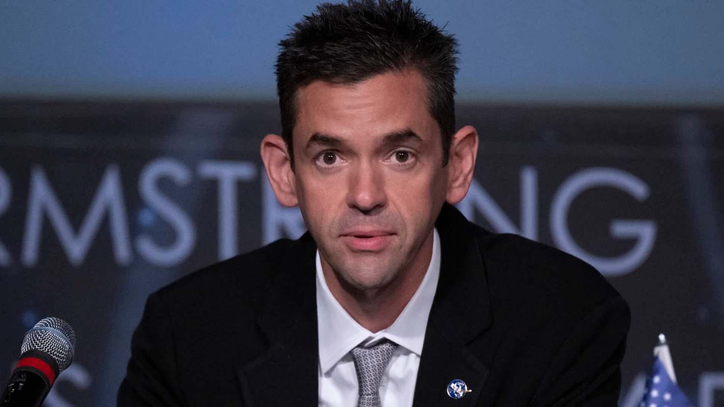 NASA Administrator Jared Isaacman speaks at a podium with a microphone, with a backdrop featuring the name "Armstrong."