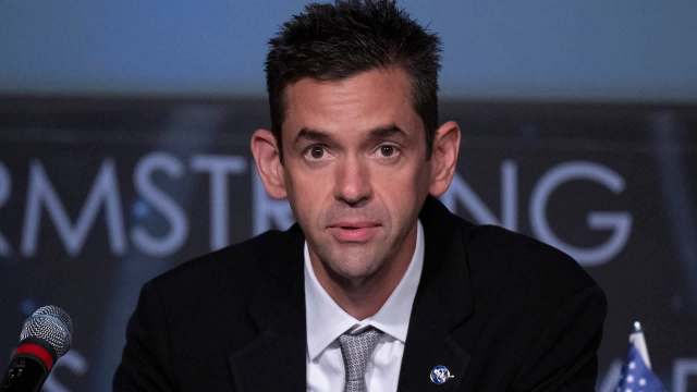NASA Administrator Jared Isaacman speaks at a podium with a microphone, with a backdrop featuring the name "Armstrong."