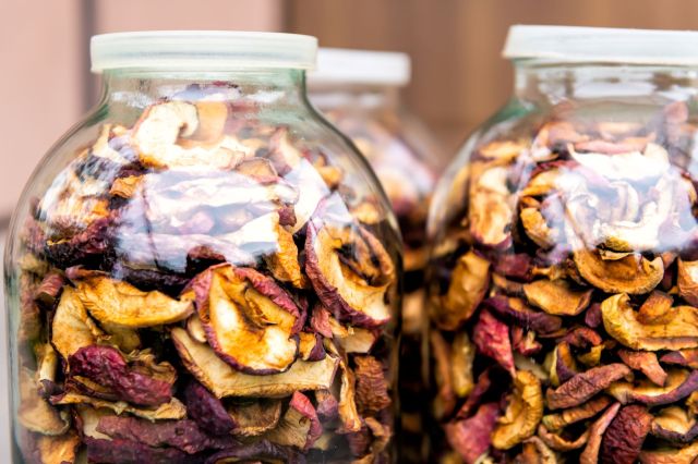 Jars filled with dried fruit slices arranged on a surface.