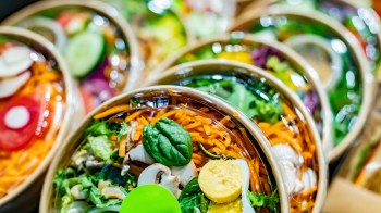 Several colorful salad bowls filled with various vegetables and ingredients.