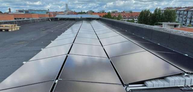 Solar panels installed on a building rooftop with gray clouds in the background.