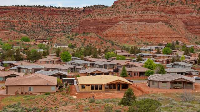 A residential neighborhood with houses and red rock formations in the background.