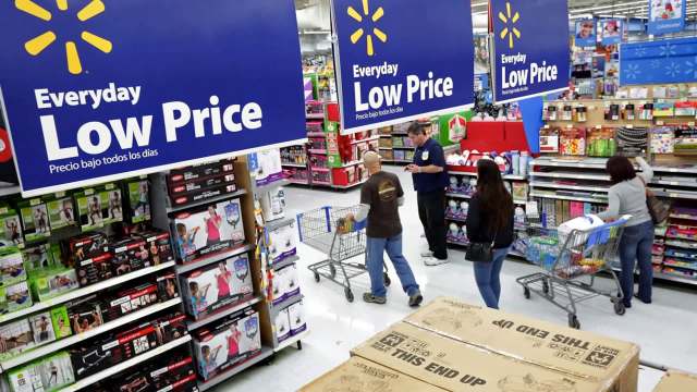 A retail store aisle with "Everyday Low Price" signs and shoppers with carts exploring various products.