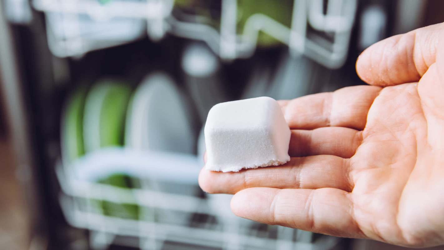 A person holding a white dishwashing tablet.