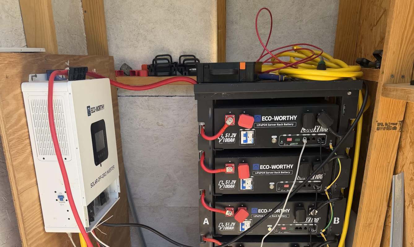 A solar inverter connected to multiple batteries in a utility shed.