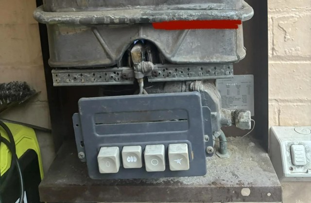 A gas appliance control panel with buttons and connected pipes, surrounded by dust.
