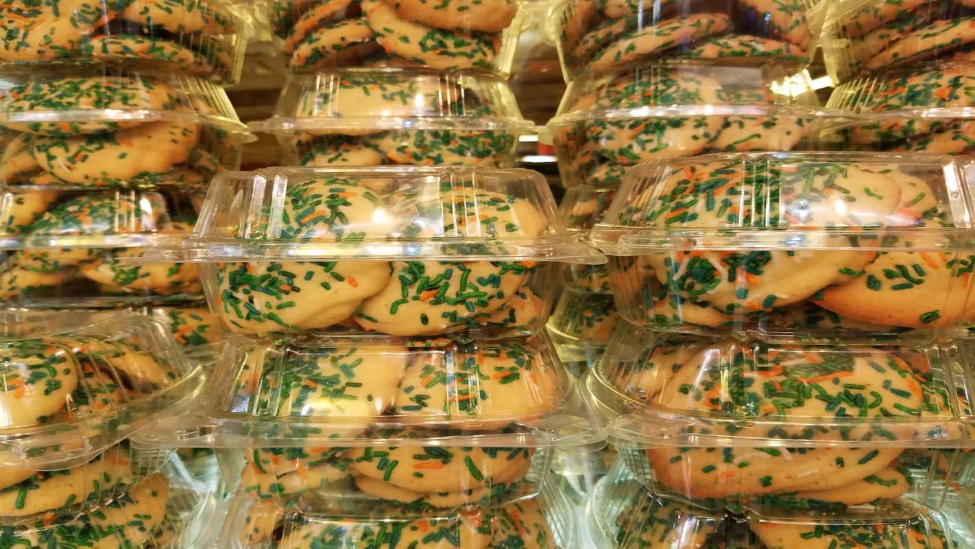 Stacks of transparent containers filled with cookies topped with green and orange sprinkles.