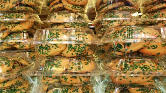 Stacks of transparent containers filled with cookies topped with green and orange sprinkles.
