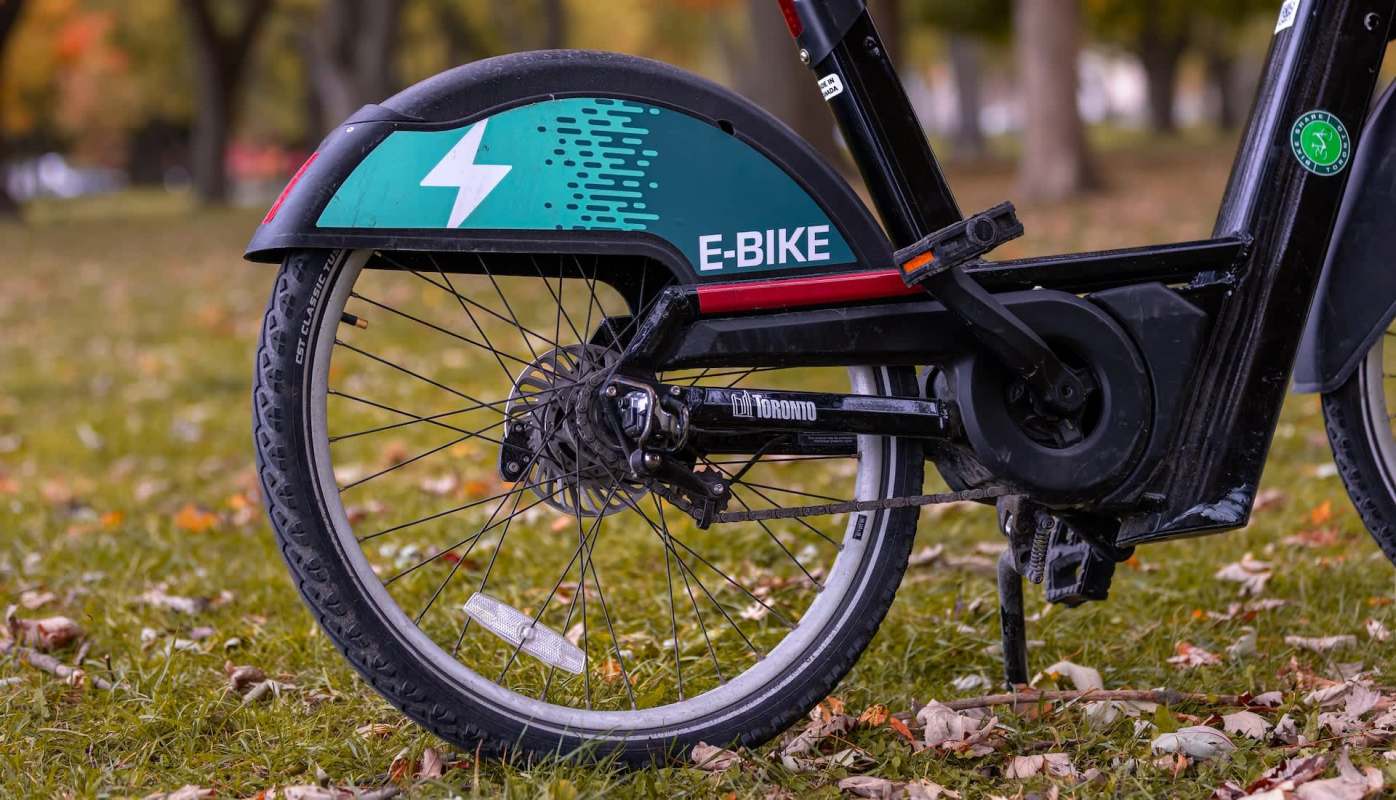 An electric bike parked on grassy ground with autumn leaves scattered around.