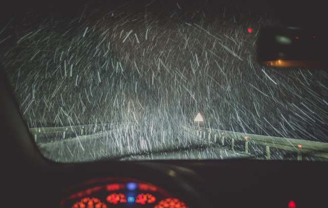 A heavy snowstorm on a dark road.