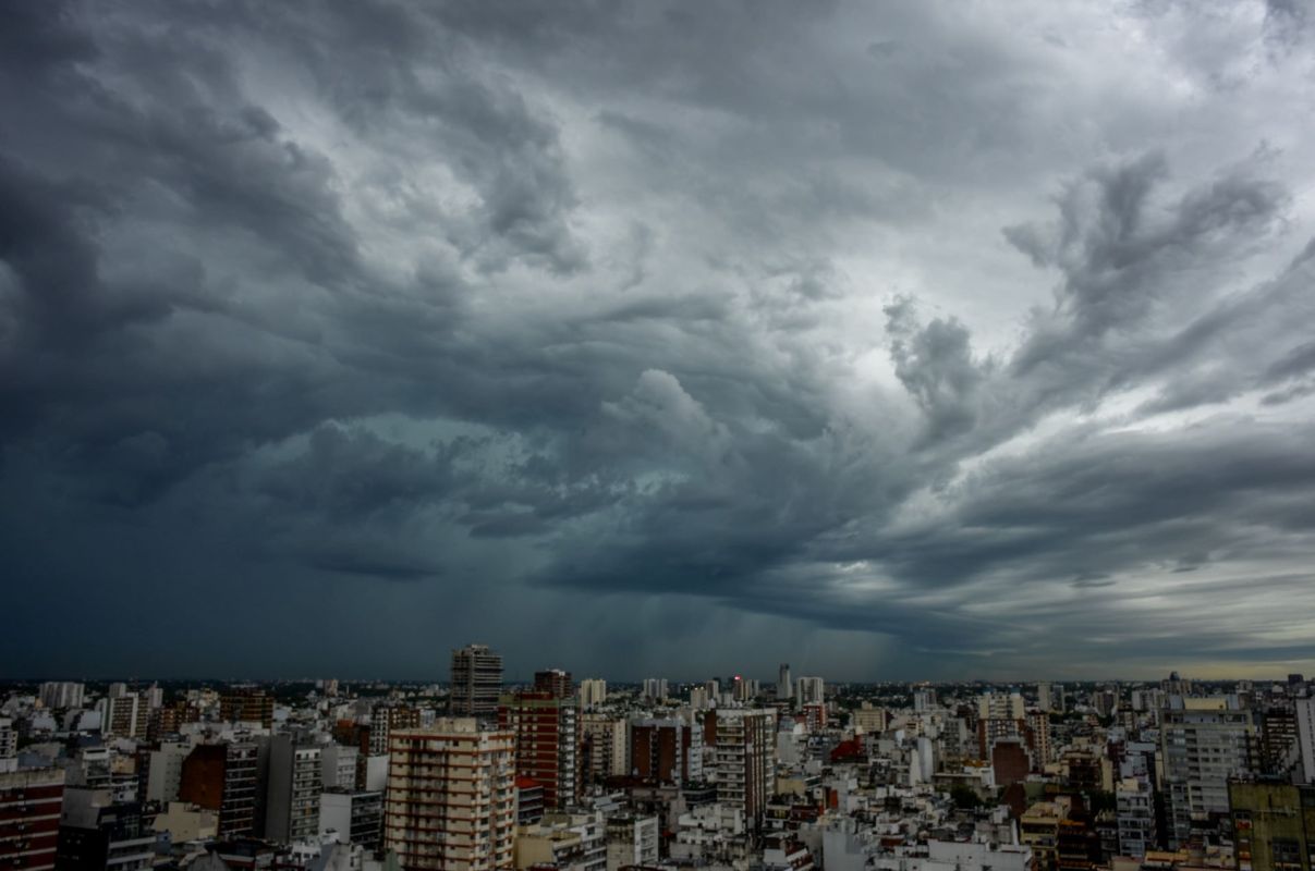 A city skyline under a dark, cloudy sky with turbulent weather patterns.