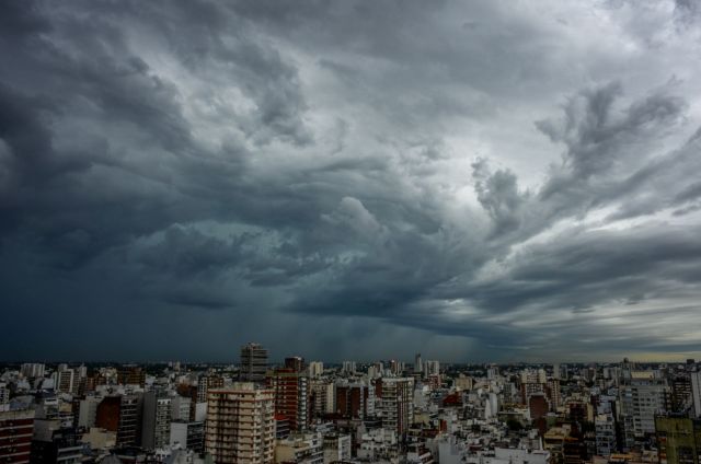 A city skyline under a dark, cloudy sky with turbulent weather patterns.