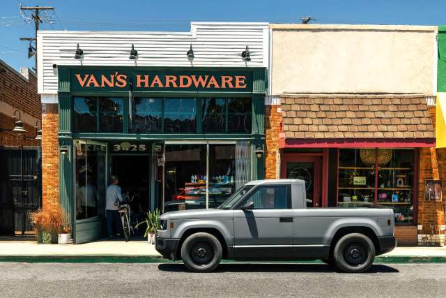A gray pickup truck parked in front of Van's Hardware store on a sunny day.